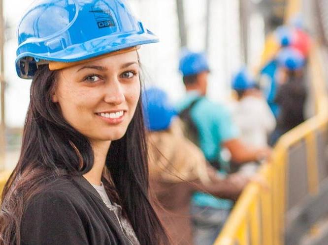 一名年轻女子在建筑工地戴着一顶蓝色安全帽