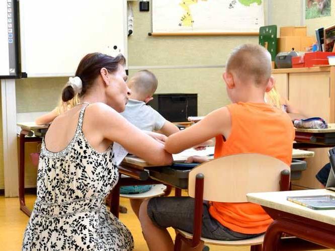 Teacher helping younger child with school work
